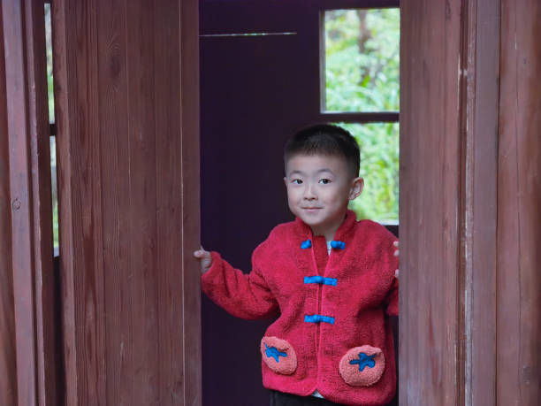 A child dressed in red opens the wooden door