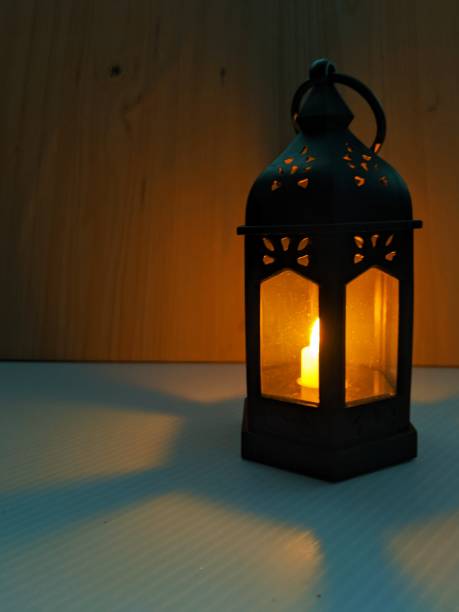 istock Black plastic candle lantern with led lights isolated on white and brown background, low light shot 2203818186