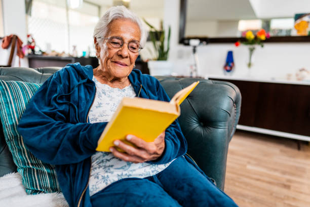 istock Senior woman reading a book on sofa at home 2203827550