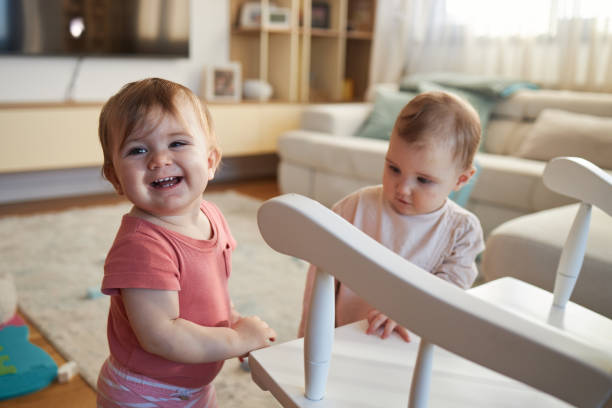 Twin baby sisters playing in domestic room.