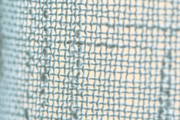 A high-detail macro photograph of interwoven white fabric, showcasing individual knots and delicate fiber textures with bright natural light. Ideal for textiles, craftsmanship, or material studies.
