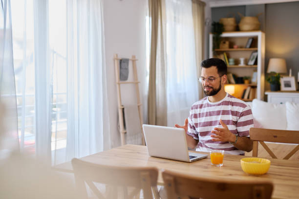 istock Young man having a video call on his laptop while having breakfast at home 2203840255