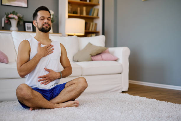 istock Young man practicing yoga and meditating at home 2203840522