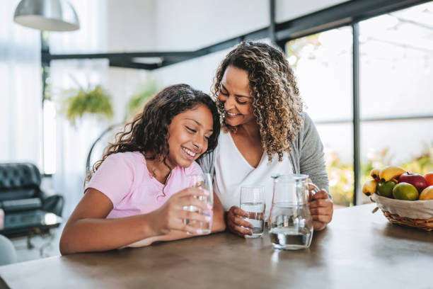istock Mother and daughter drinking water together 2203845548