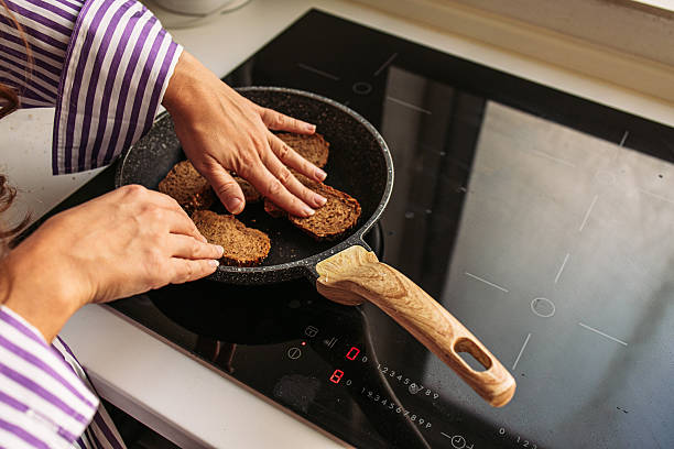 istock Woman pressing bread on a pan to make a toast 2203847468