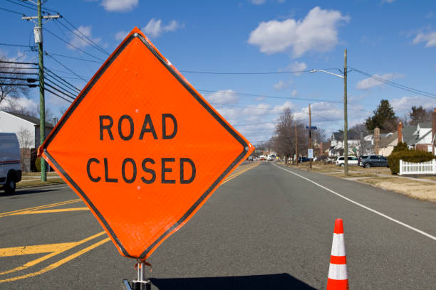 Road closed detour sign in residential neighborhood.