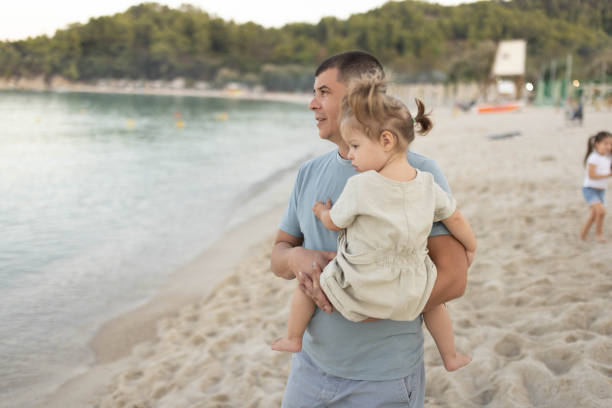 istock Father holding his one-year-old child on the seashore. 2203854490