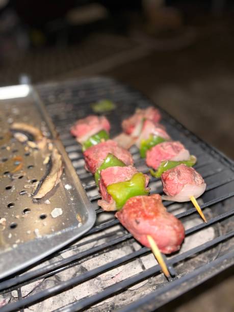 Grilling steak kebab with onion and green peppers. Mushrooms on the side.