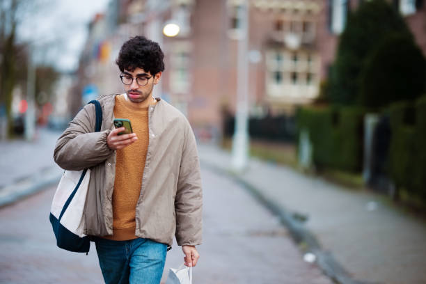 istock Young Man Walking in City Checking Smartphone on a Cool Day 2203869479