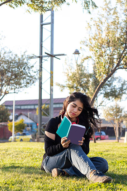 istock young woman sitting on the lawn reading a book 2203878016
