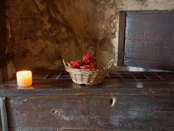 istock Little dried peppers in a basket, candle burning beside 2203883244