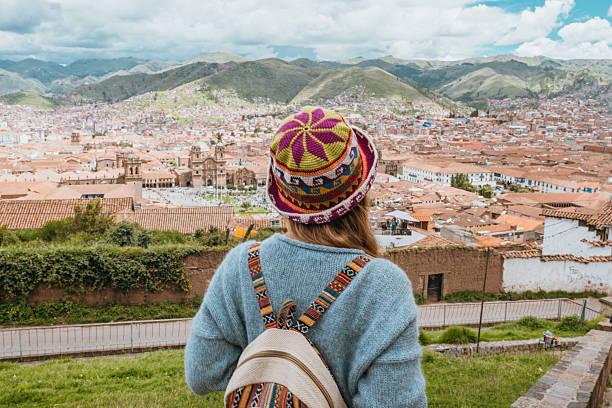 Young woman in colorful hat overlooks historic cityscape. Scenic view of ancient architecture and rolling hills. Travel and adventure in cultural destination.