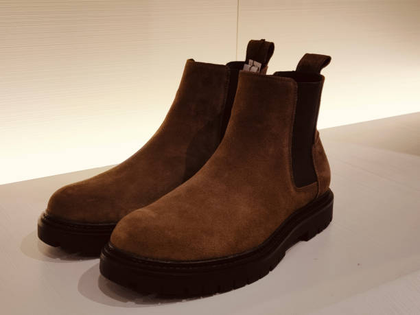 istock A pair of brown boots with black soles and tan velvet upper material, displayed on an empty white surface 2203890477