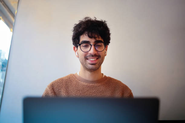 istock Smiling Man with Curly Hair Using a Laptop in a Comfortable Setting 2203890880