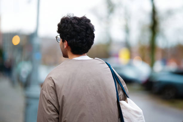 istock Man Walking Outdoors in City Setting with Blurred Urban Background 2203890881