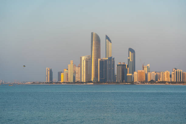 Abu Dhabi, UAE, January 28, 2025: Abu Dhabi skyline with ADNOC Headquarters and Etihad Towers reflecting sunset over the Arabian Gulf, editorial image