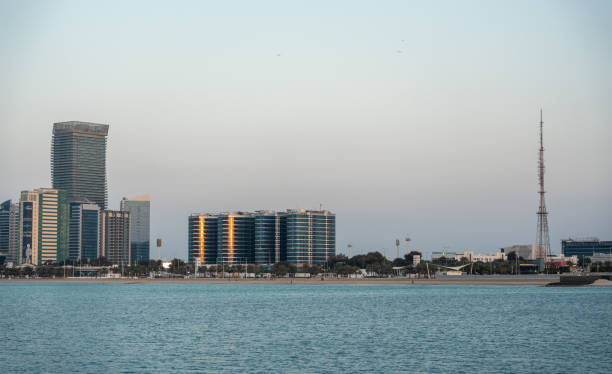 Abu Dhabi, UAE, January 28, 2025: Landmark Tower and Corniche Towers in Abu Dhabi reflecting sunset over the Arabian Gulf waterfront, editorial image