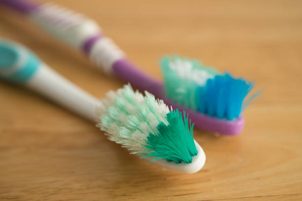 Close up old used destroy bent bristle toothbrush on wooden table background. Dental care, healthcare, unhygienic, time to change the new toothbrush concept.