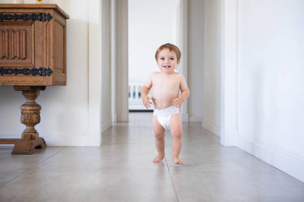 Cute baby boy in diapers taking his first steps at home - Buenos Aires - Argentina