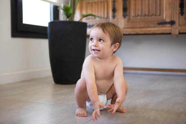istock Cute baby boy in diapers squatting at home 2203897405