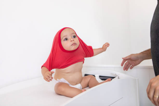 Young father dressing his baby boy on the baby changing table