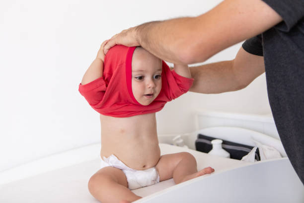 istock Young father dressing his baby boy on the baby changing table 2203897431