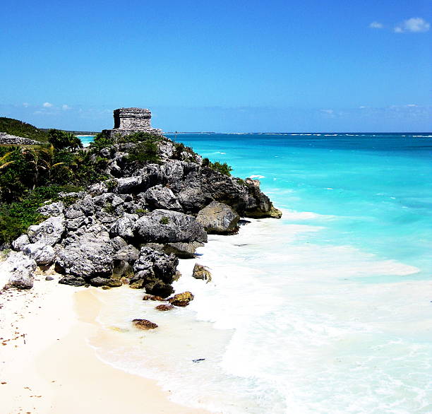 istock Tulum unites ancient Maya ruins with breathtaking Caribbean coastline. Stone temples perch dramatically on limestone cliffs above pristine white beaches and impossibly turquoise waters. 2203901612