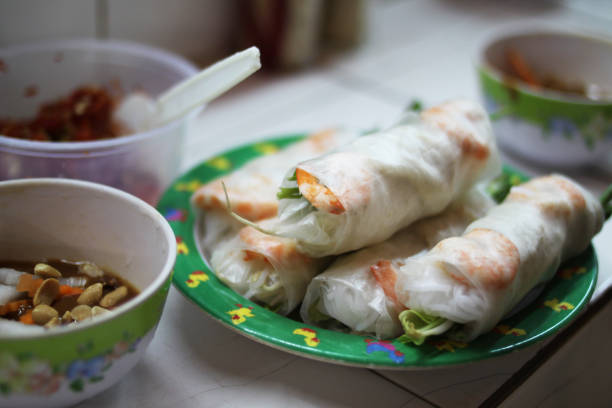 Close-up of fresh Vietnamese spring rolls with shrimp and greens served with traditional dipping sauces