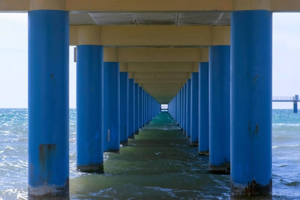 istock Sea under pier among parallel blue columns making narrow corridor in water. 2203905273