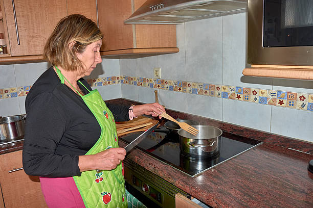 istock Grandmother preparing a meal in a modern kitchen with fresh ingredients and cookware 2203906922
