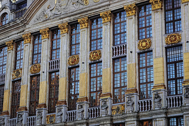 Brussels Detailed facade of an old building featuring rows of windows framed by gilded columns and intricate stone carvings, showcasing European architectural design.