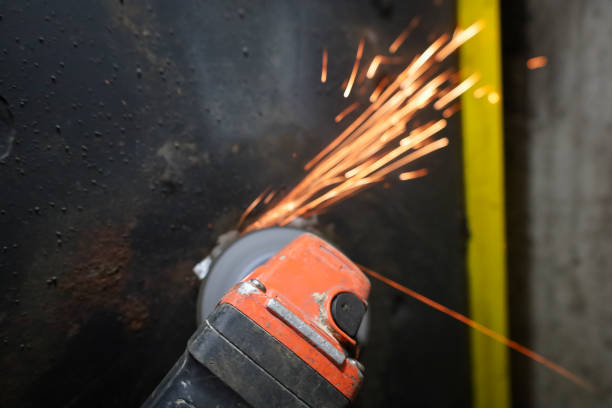 istock A hand holding an angle grinder from which sparks are flying is visible. The sparks are bright orange in color, creating a contrast with the dark metal surface. 2203909691
