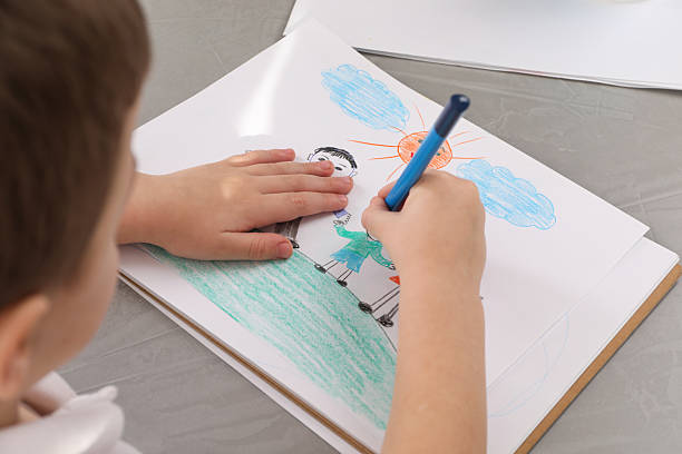 istock Little boy drawing with pencil at grey textured table, closeup. Child`s art 2203910501