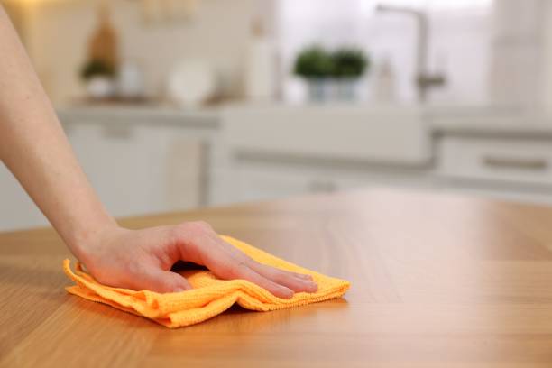 istock Woman with microfiber cloth cleaning wooden table in kitchen, closeup. Space for text 2203911894