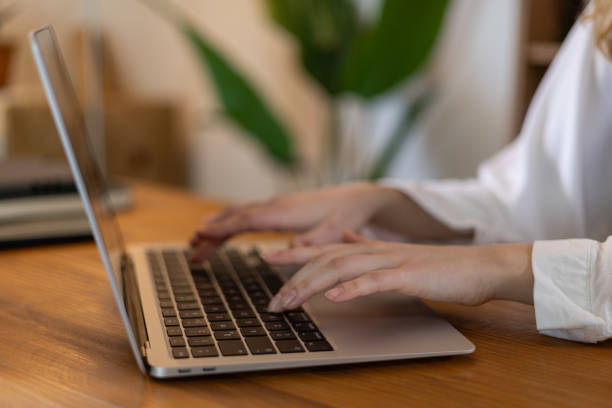 istock Female telecommuter typing on laptop keyboard while working remotely from home office 2203912118