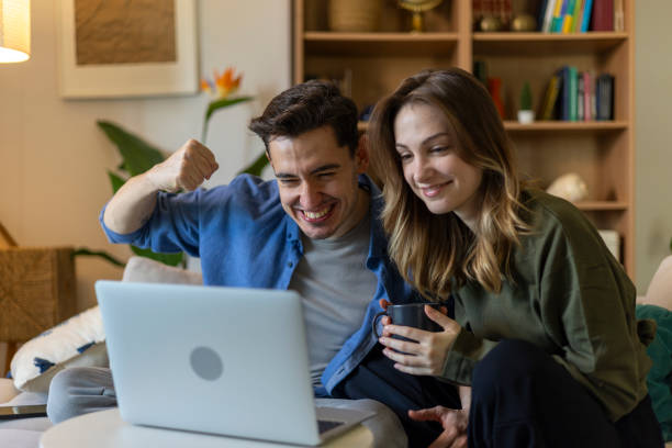 istock Excited couple celebrating success while watching laptop at home 2203912661