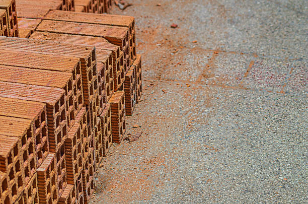 Stacks of orange bricks sit atop a partially finished building, showcasing construction progress on a sunny day.