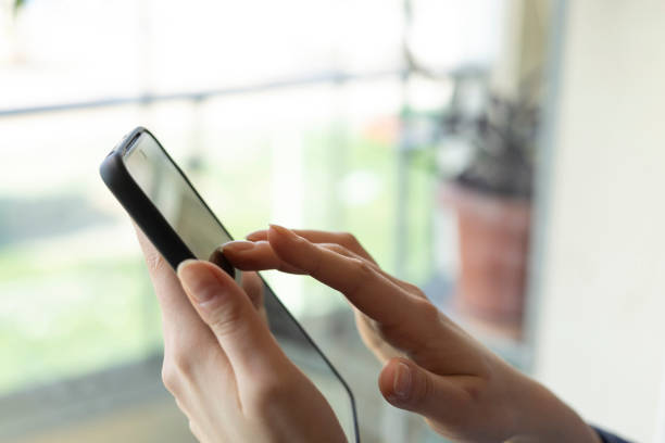 istock Woman using mobile phone, browsing internet, checking social media, ordering online by the window 2203913136