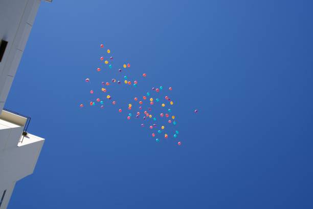 The colorful balloons floating in a clear blue sky with scattered clouds