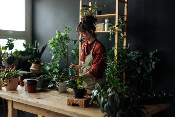 istock Young woman watering plants in her workshop 2203914209