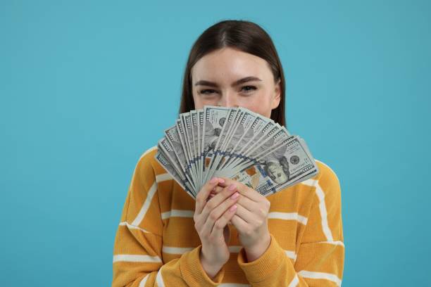 istock Woman with dollar banknotes on light blue background 2203914464