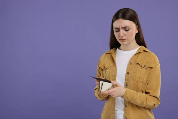 istock Sad woman with empty wallet on purple background, space for text 2203914469