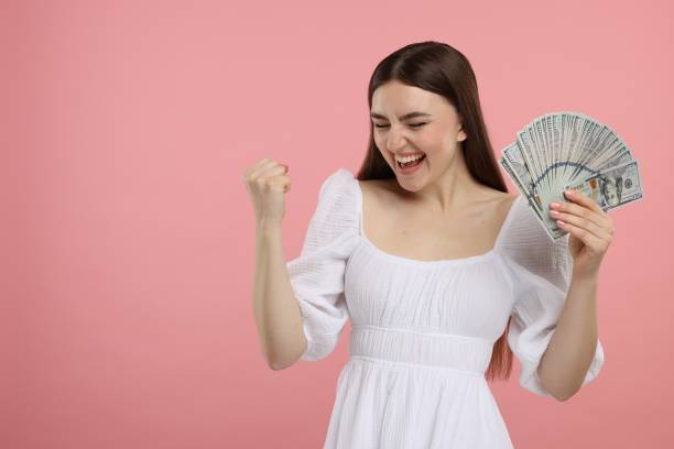 istock Excited woman with dollar banknotes on pink background, space for text 2203914612