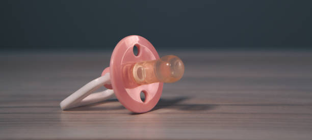 pink baby pacifier on a wooden background. copy space, top view.