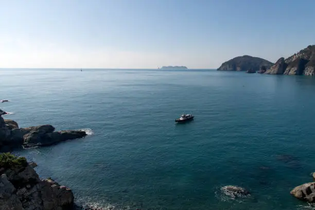 fishing boat floating on the sea surrounded by the island cliffs fishing boat floating on the sea surrounded by the island cliffs