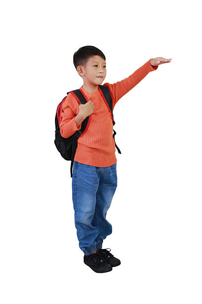 istock Asian boy child with backpack bag looking forward copy space and beckon someone by his hand isolated on white background. Image full length. 2203919947