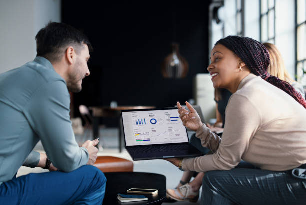 Collaborative Business Team Reviewing Data on Laptop in Modern Office Environment