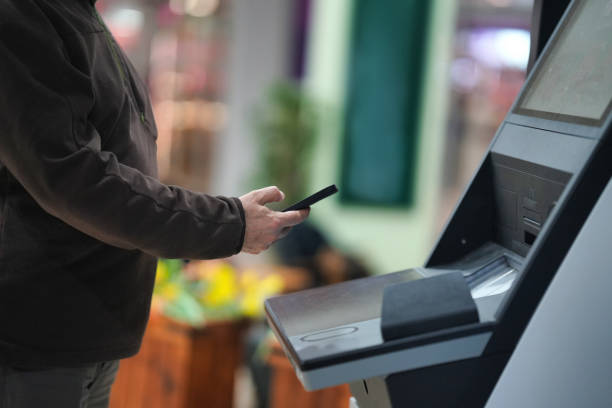 istock Man Holding a Smartphone Near a Banking Kiosk 2203927581