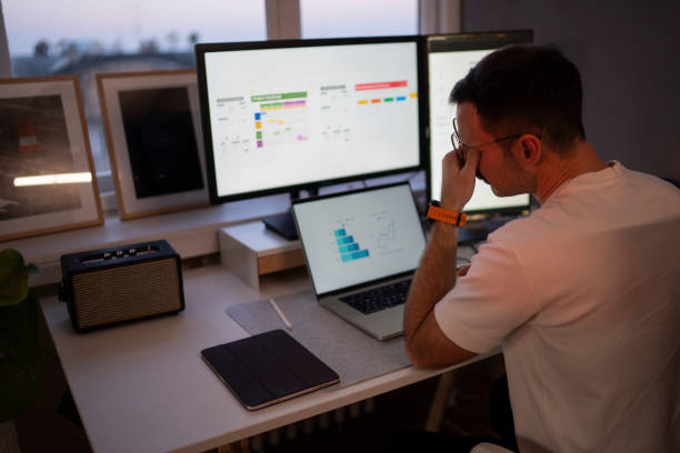 istock Stressed businessman working from home office looking at graphs on multiple screens 2203935090
