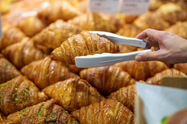 istock Hand Picking a Freshly Baked Croissant in a Bakery 2203935729